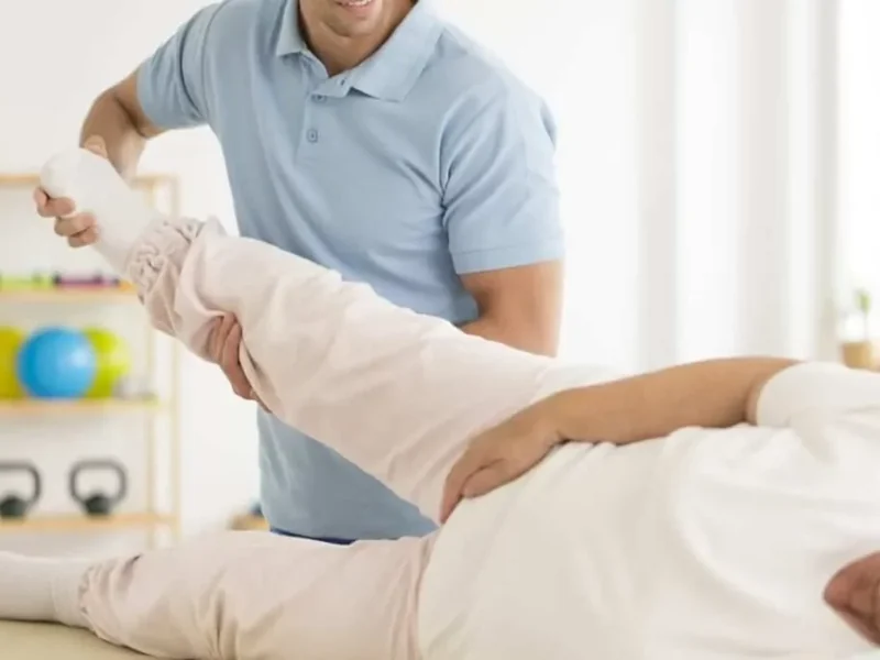 Physical therapist assessing a patient's hip and knee on a treatment table