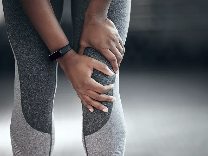Close-up of hands holding a painful knee