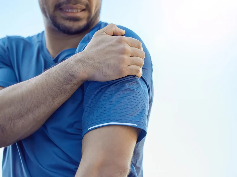 Person holding a painful shoulder joint