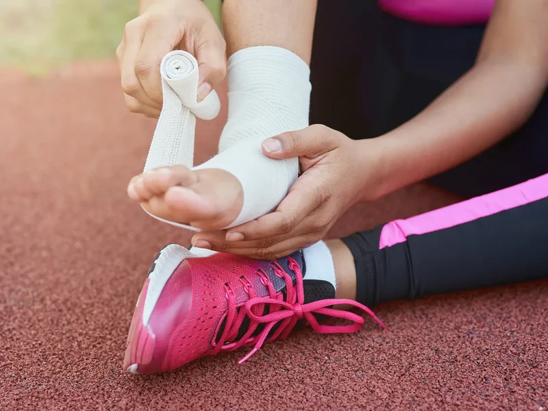 Athletic trainer taping an injured ankle on a track