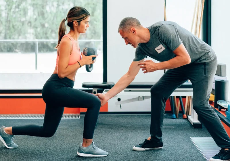 Coach guiding a client through a strength exercise